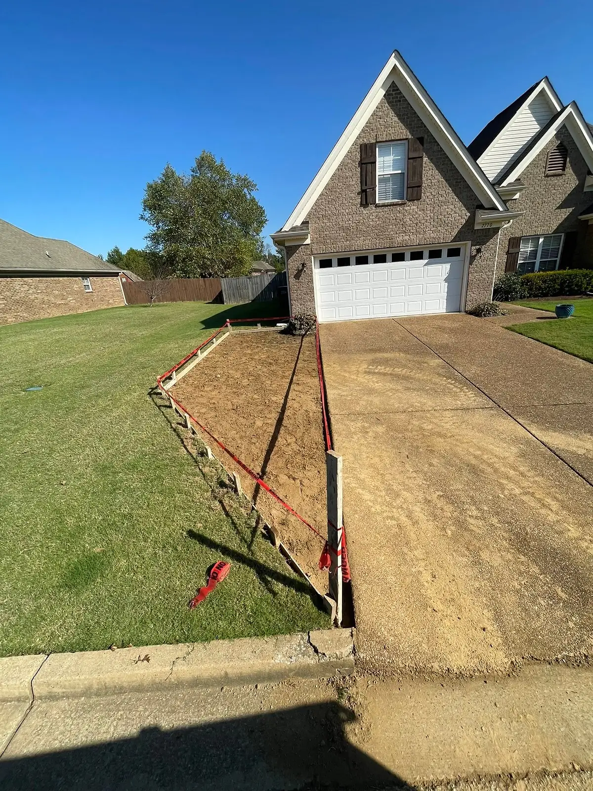 Compacted sand base and string lines set for a new driveway