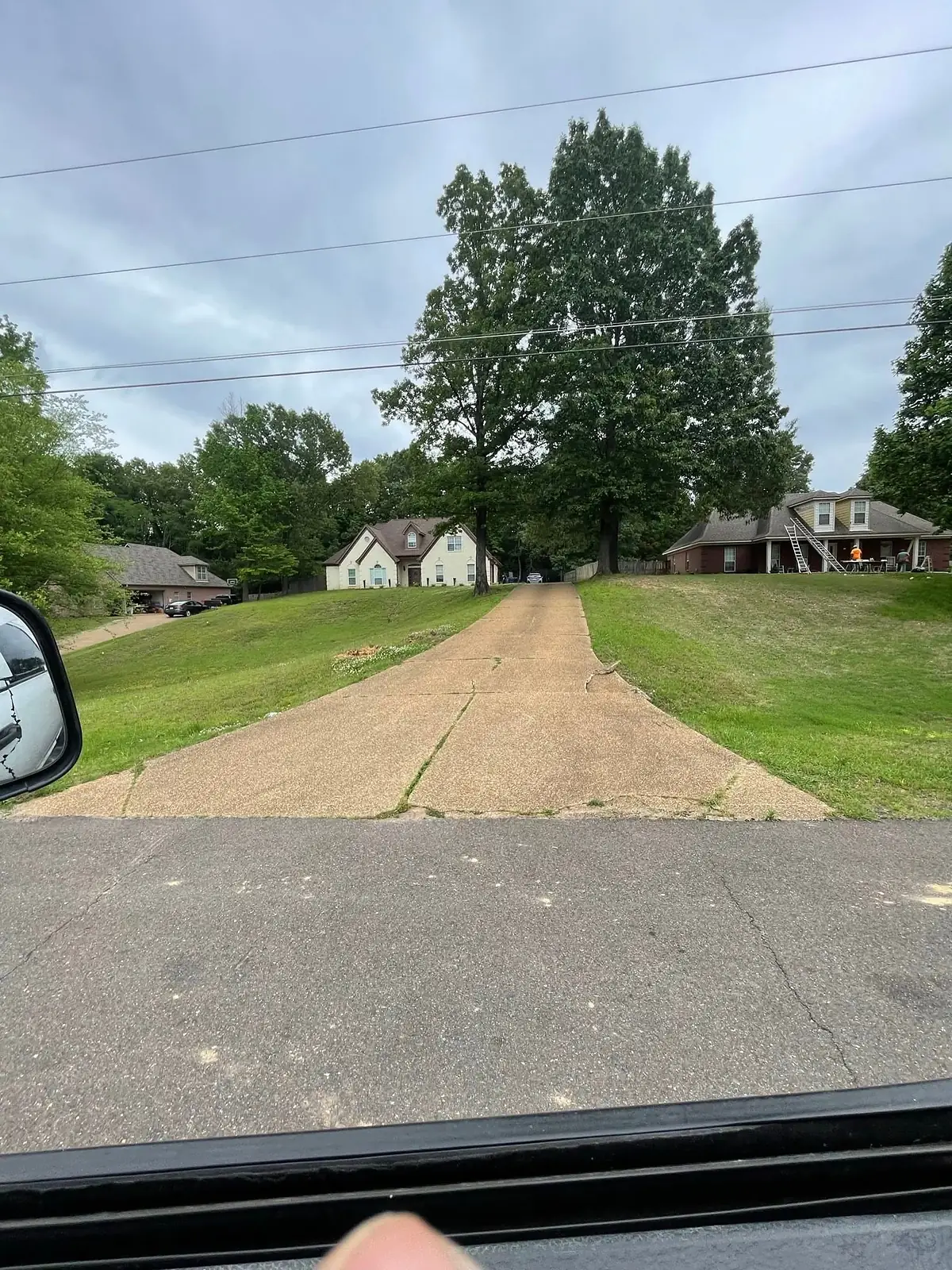 Narrow cracked driveway running up a slope before replacement