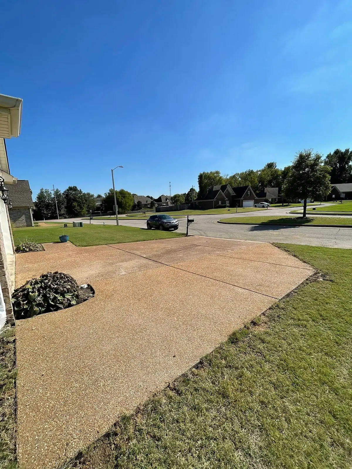 Exposed aggregate driveway sweeping across a green suburban lawn