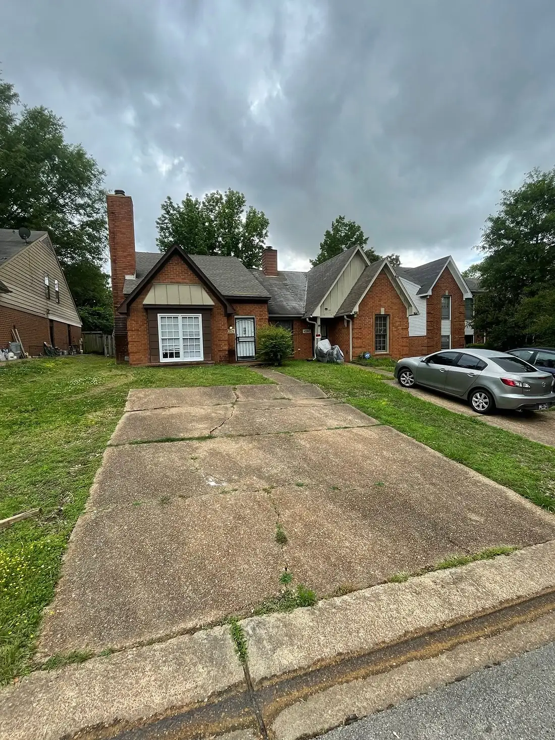 Cracked driveway panels breaking apart in front of a brick home