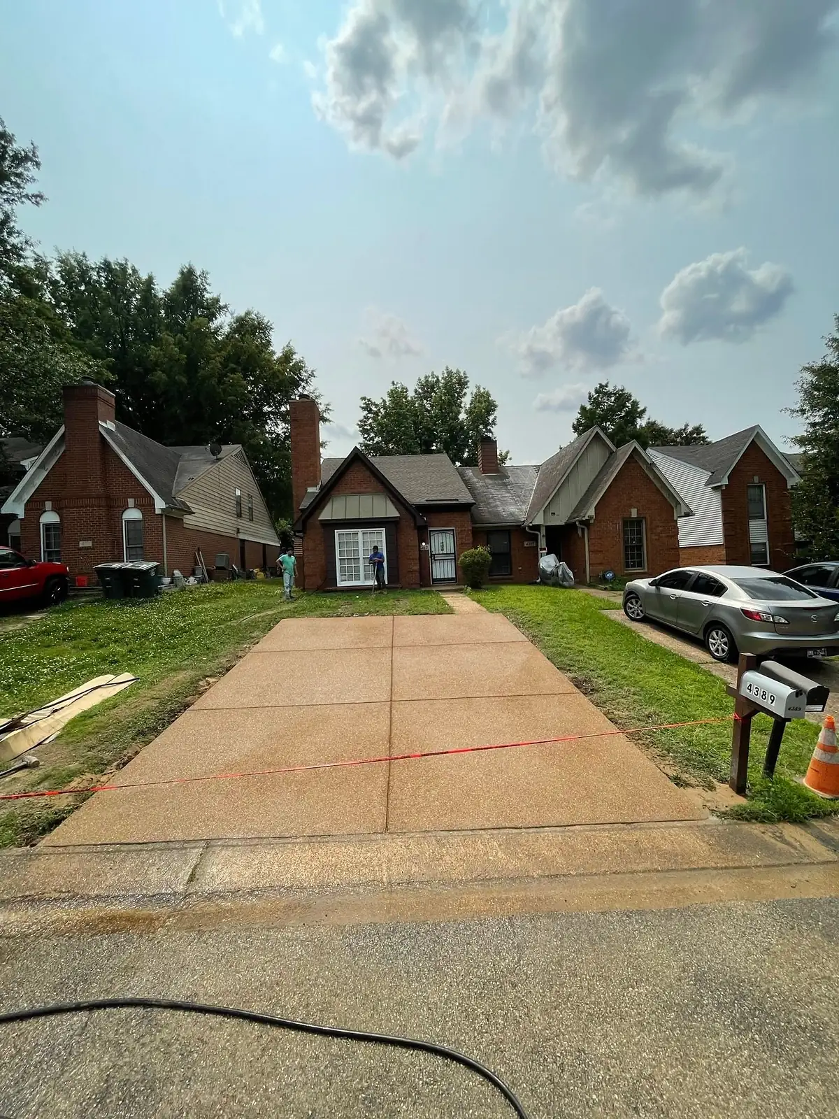 Worn and discoloured driveway in front of a brick ranch house