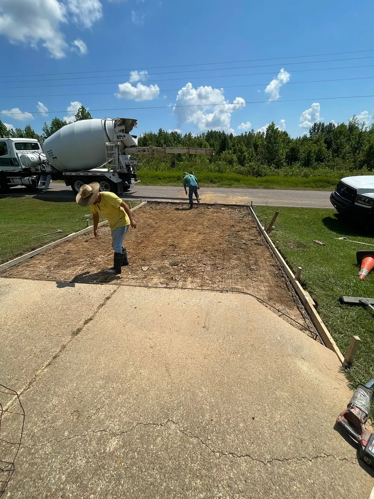 Worker preparing the sub base with a mixer truck waiting at the street