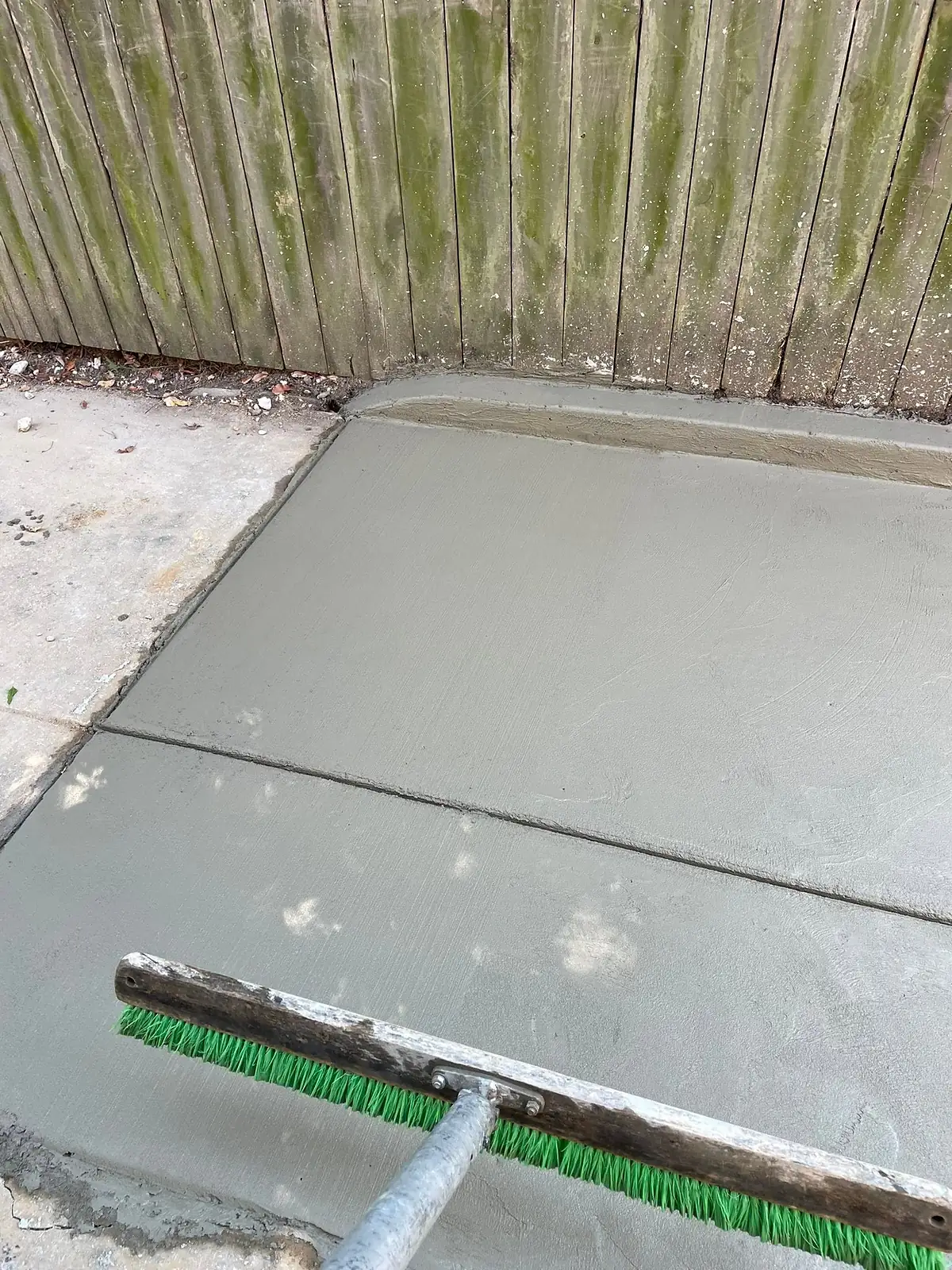 Broom being drawn across wet concrete to create a non slip finish