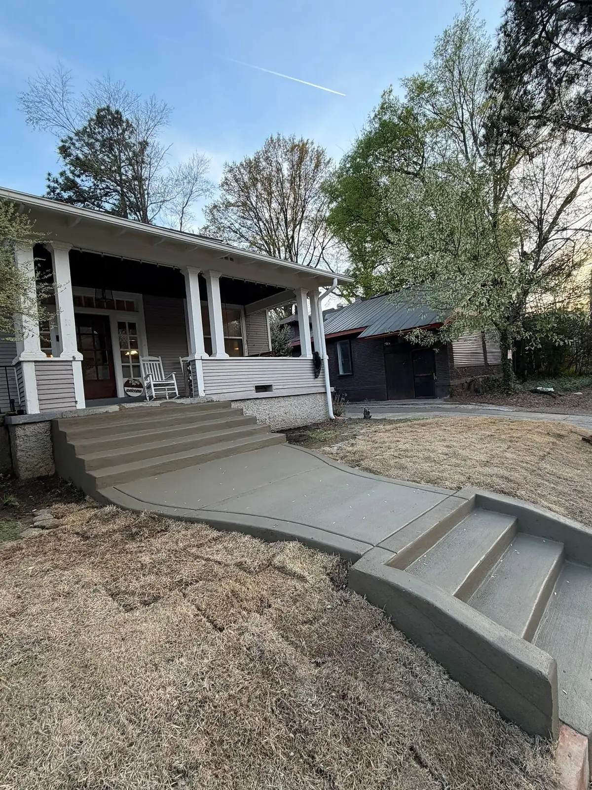 New concrete steps and curved walkway leading up to a white porch