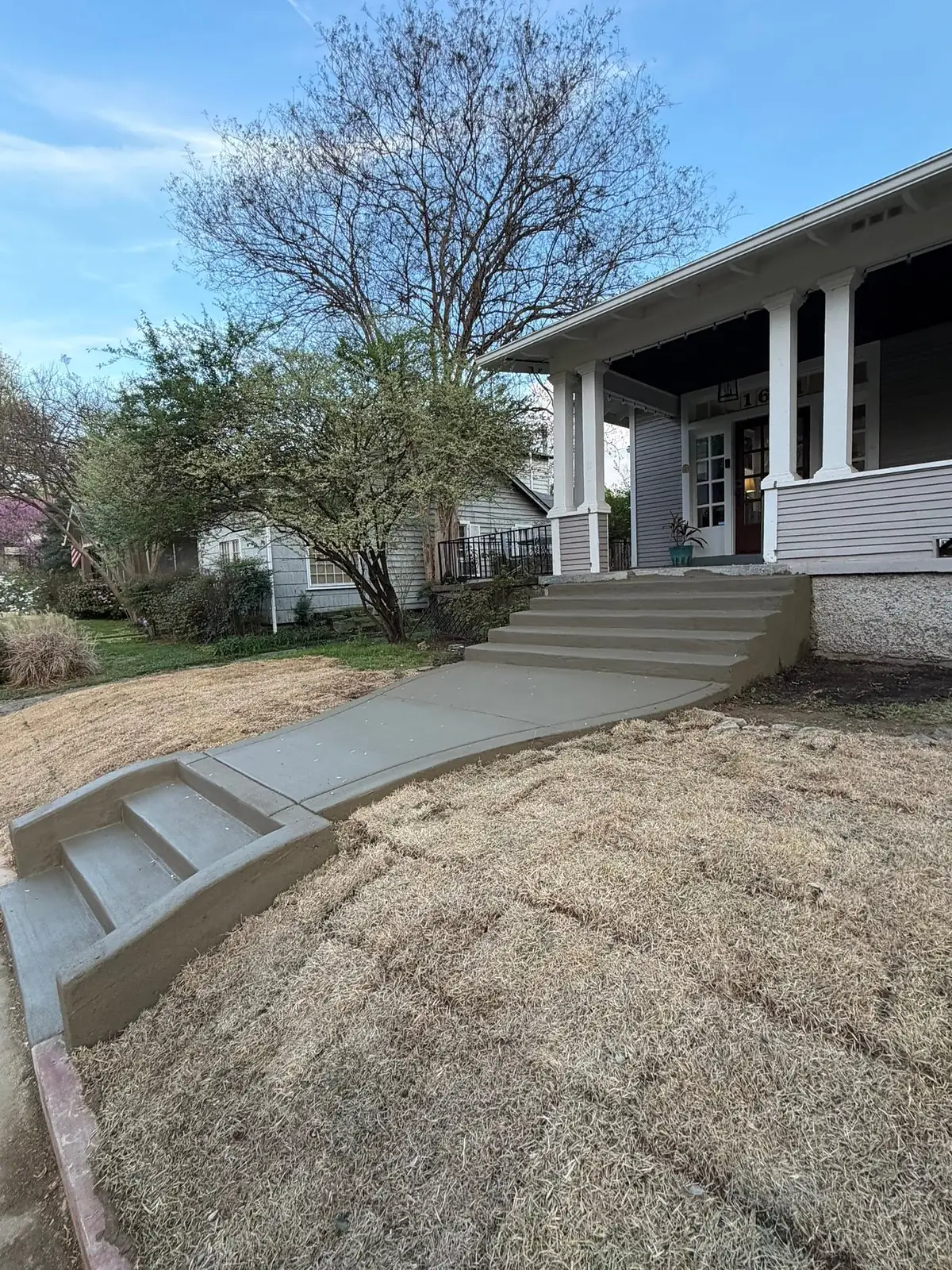 Curved concrete path and steps finished in front of a craftsman home