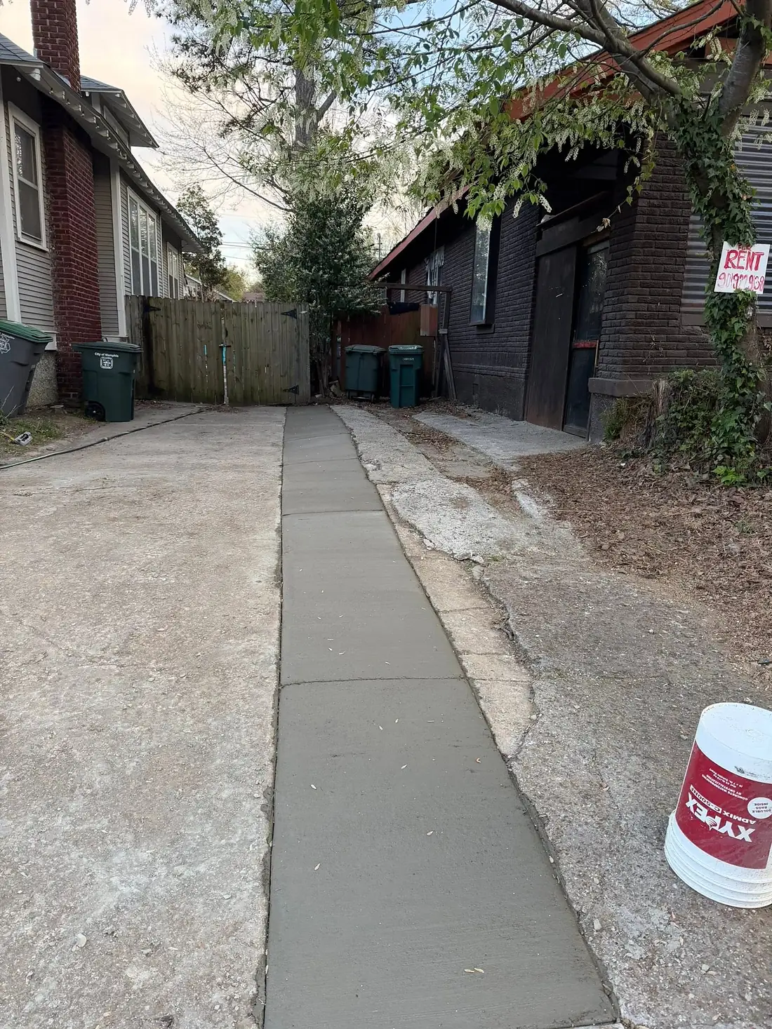 Uneven sidewalk slabs running between two houses before repair