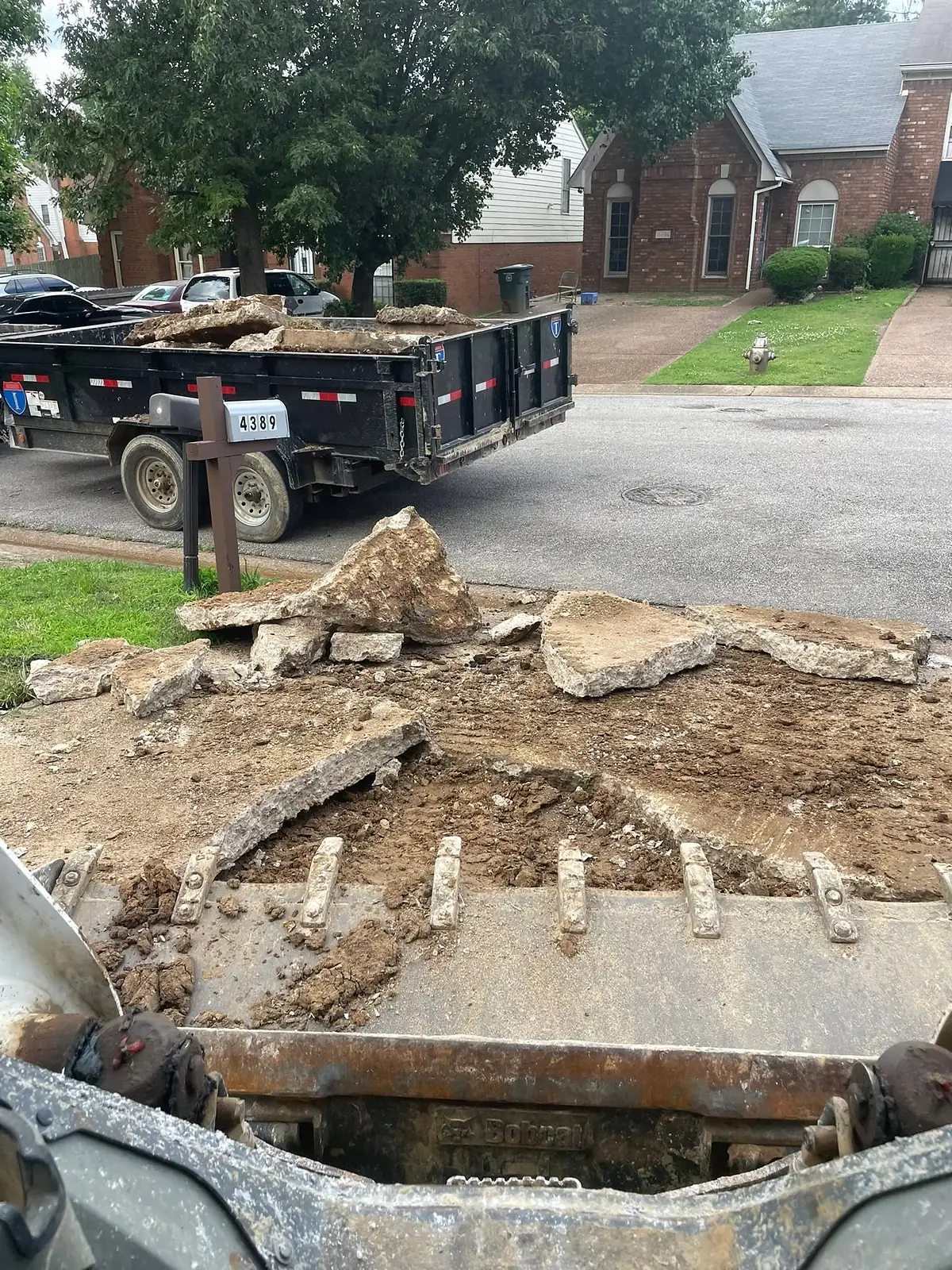 Broken concrete loaded into a dump trailer parked at the kerb