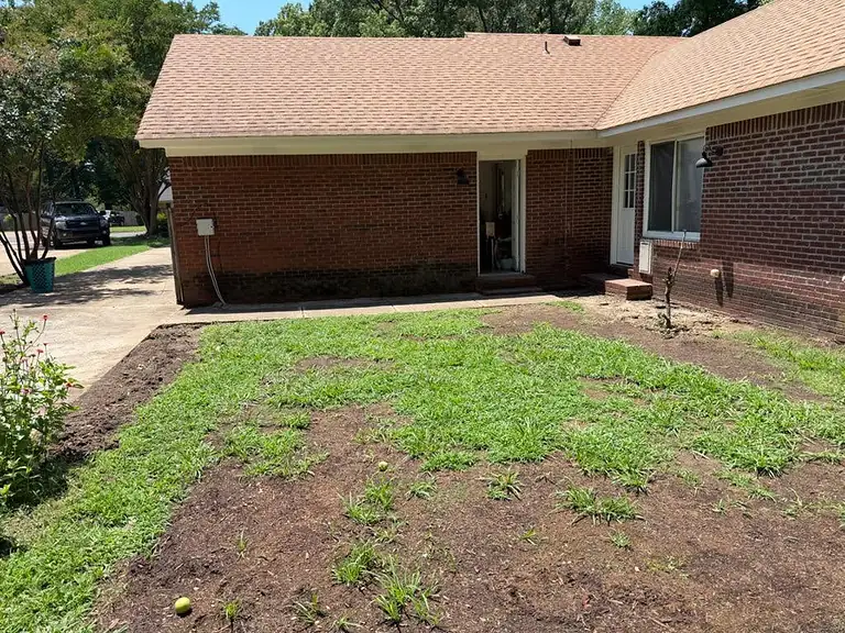 Bare dirt and patchy grass where the old driveway was removed