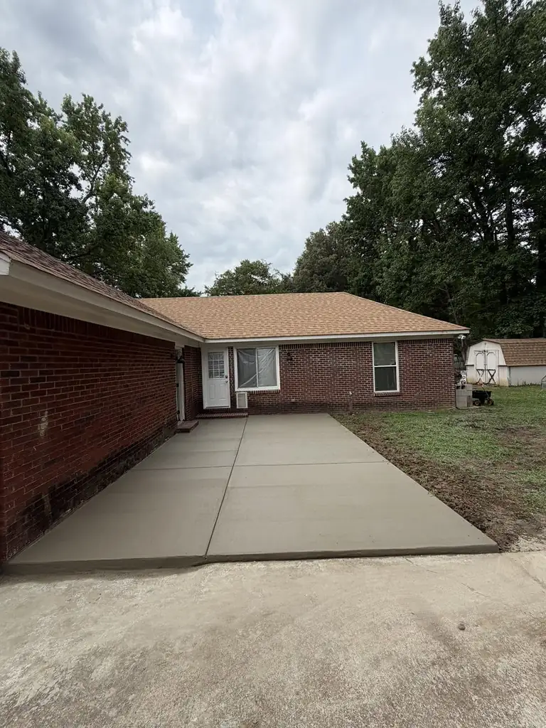 New concrete driveway with clean control joints next to a brick house