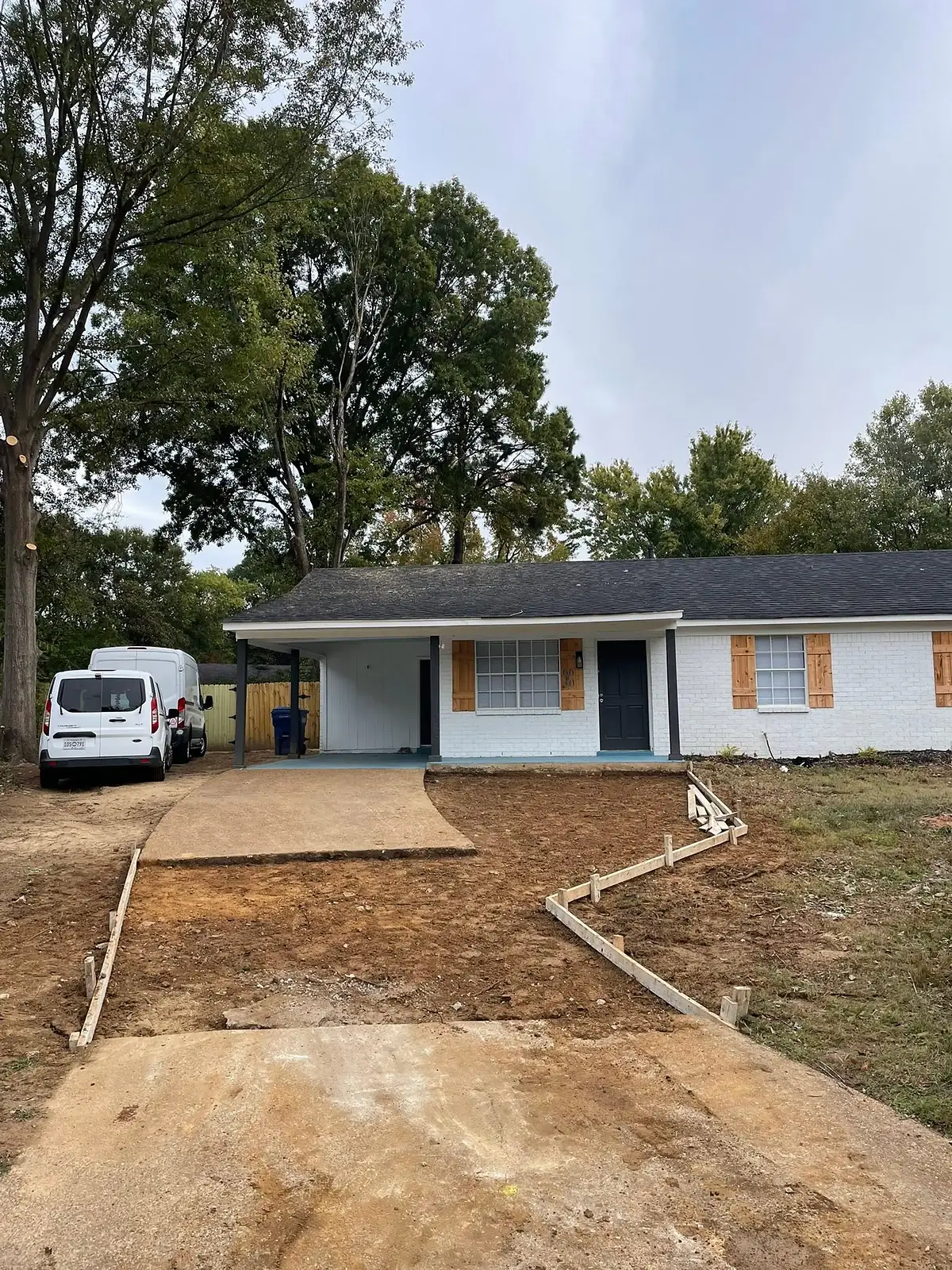 Old stained driveway and bare lawn in front of a single storey home