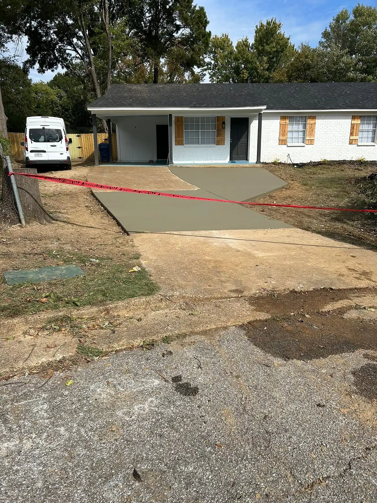 Fresh concrete driveway being placed and levelled beside a work van