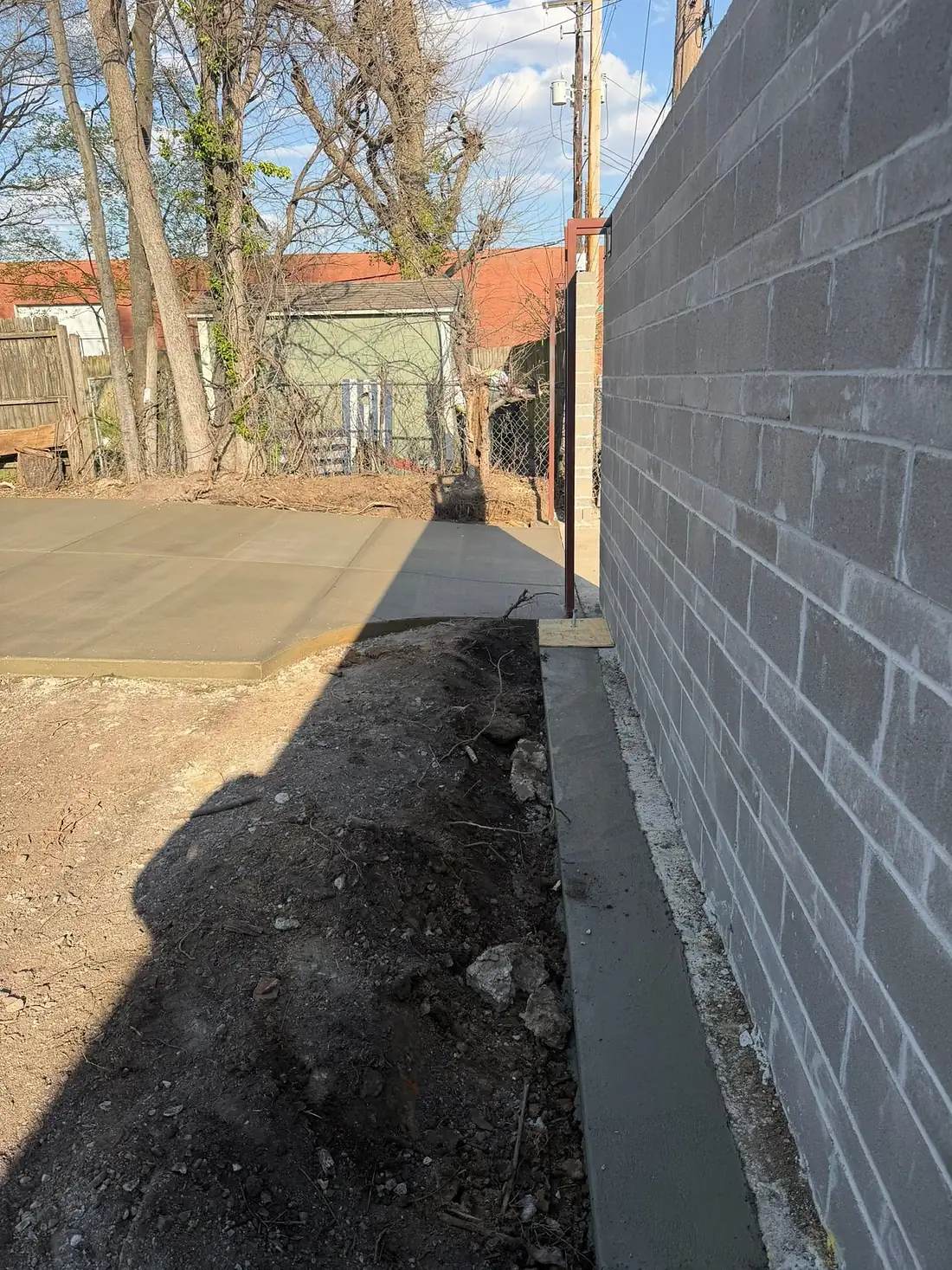 Narrow concrete slab poured tight against a grey block wall
