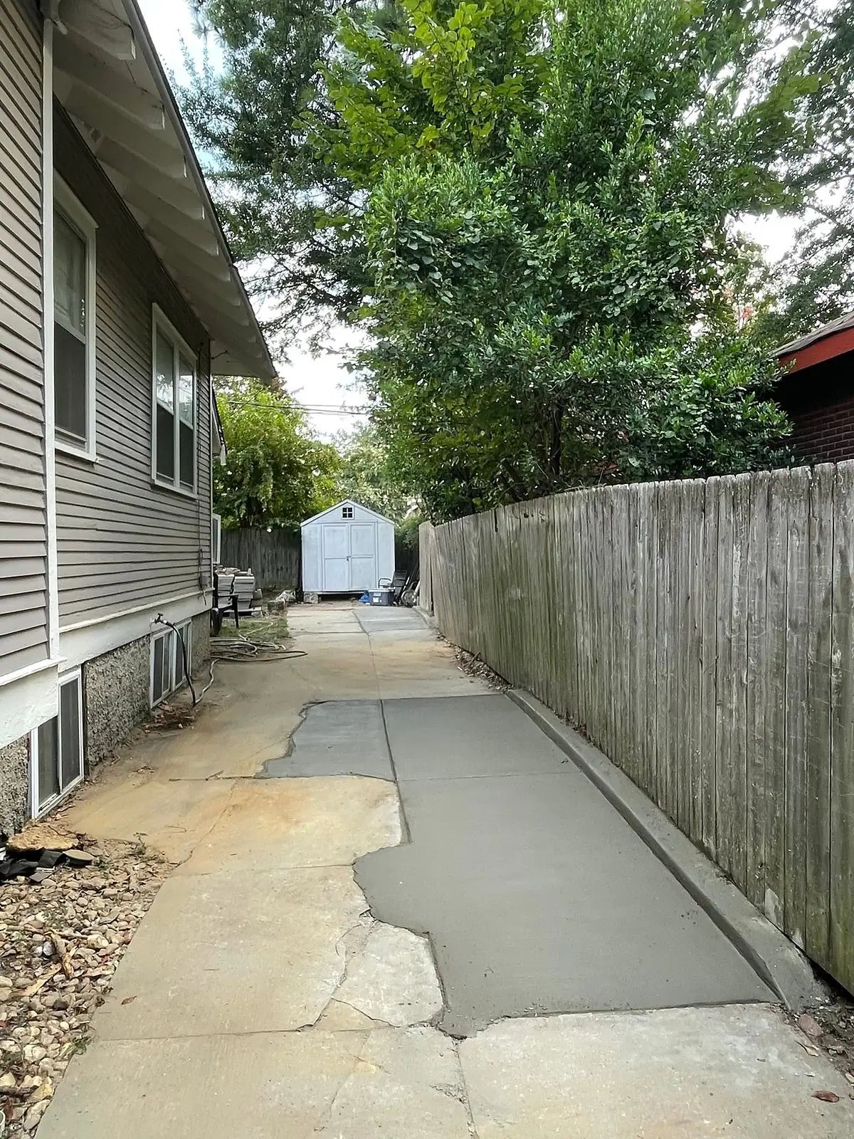 New concrete poured along a narrow side yard between house and fence