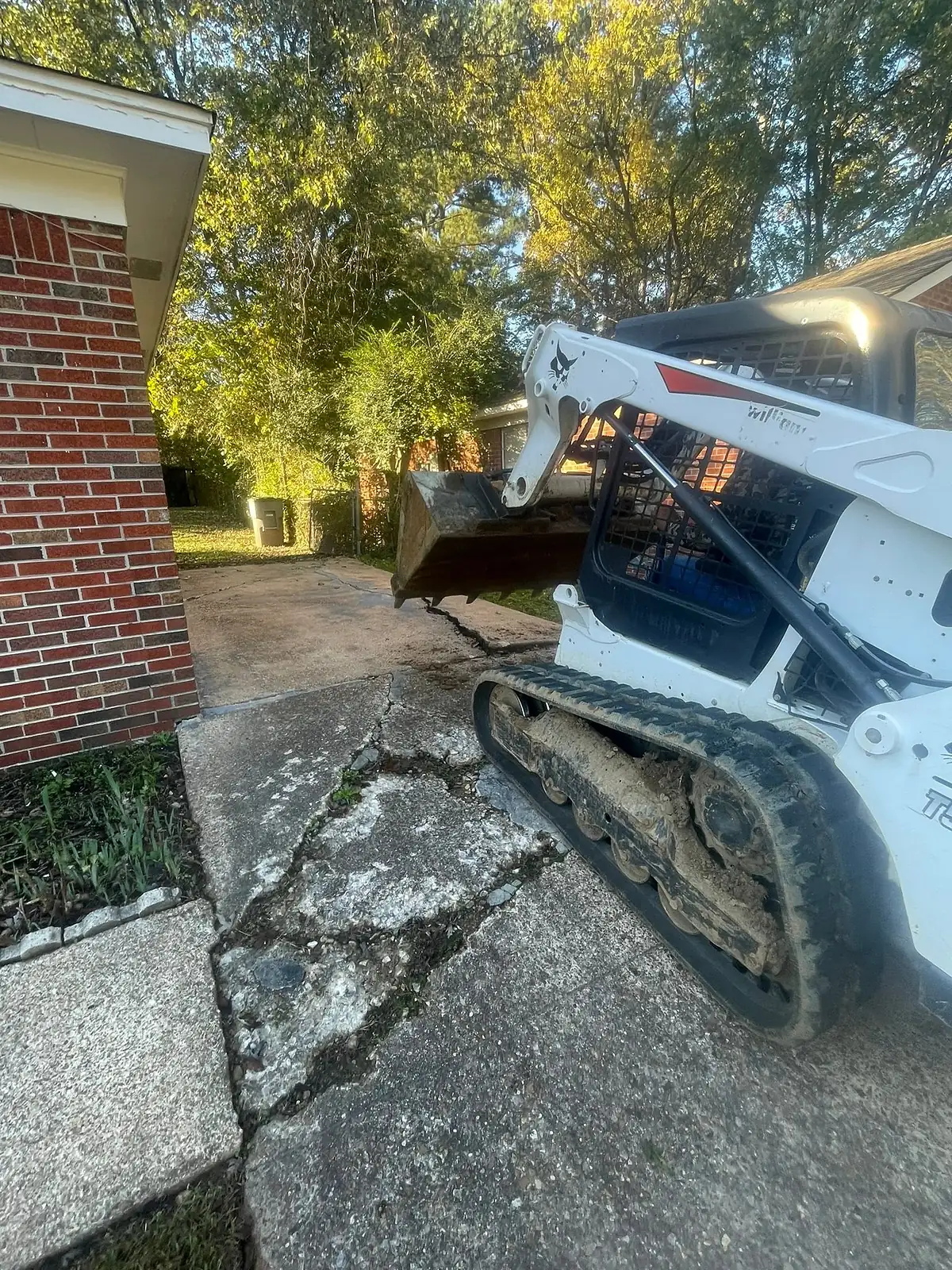 Skid steer breaking out a cracked concrete driveway section