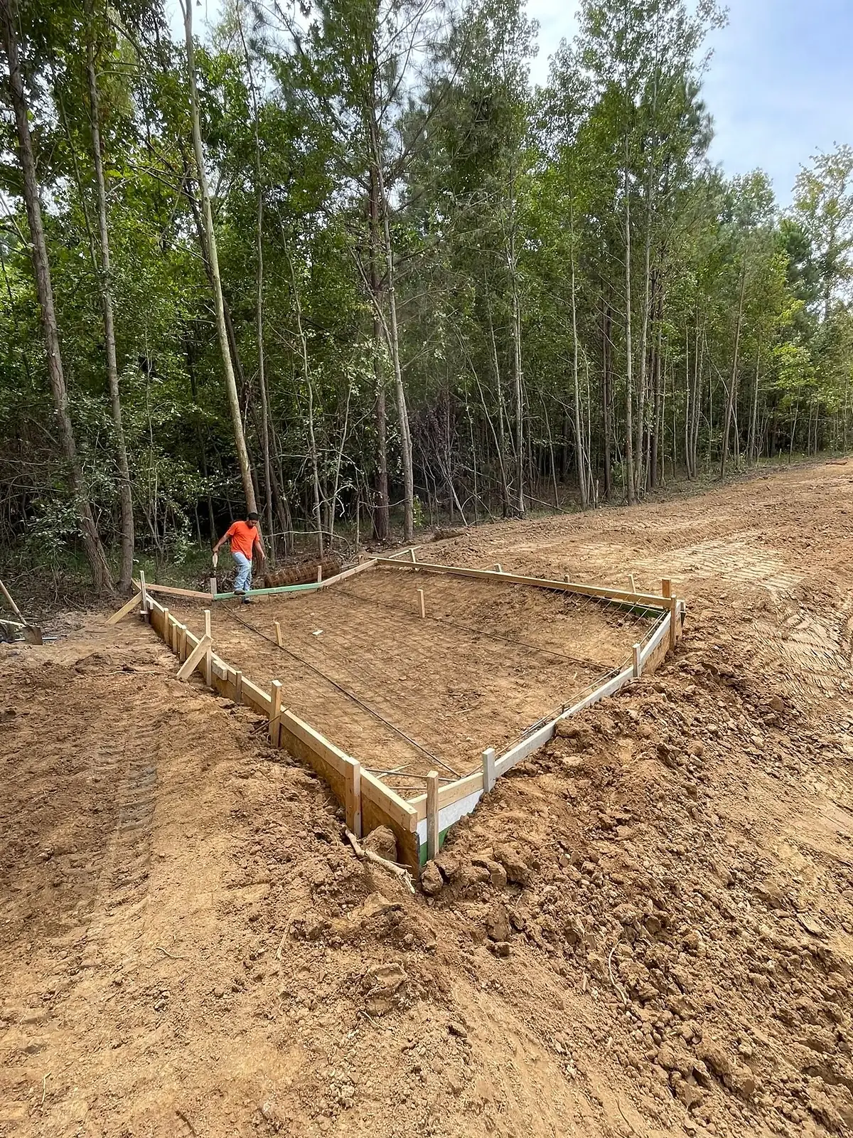 Worker setting long timber forms for a foundation slab