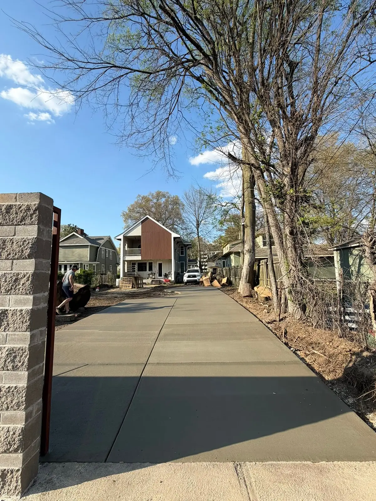 New concrete walkway running between a block wall and a wooden fence