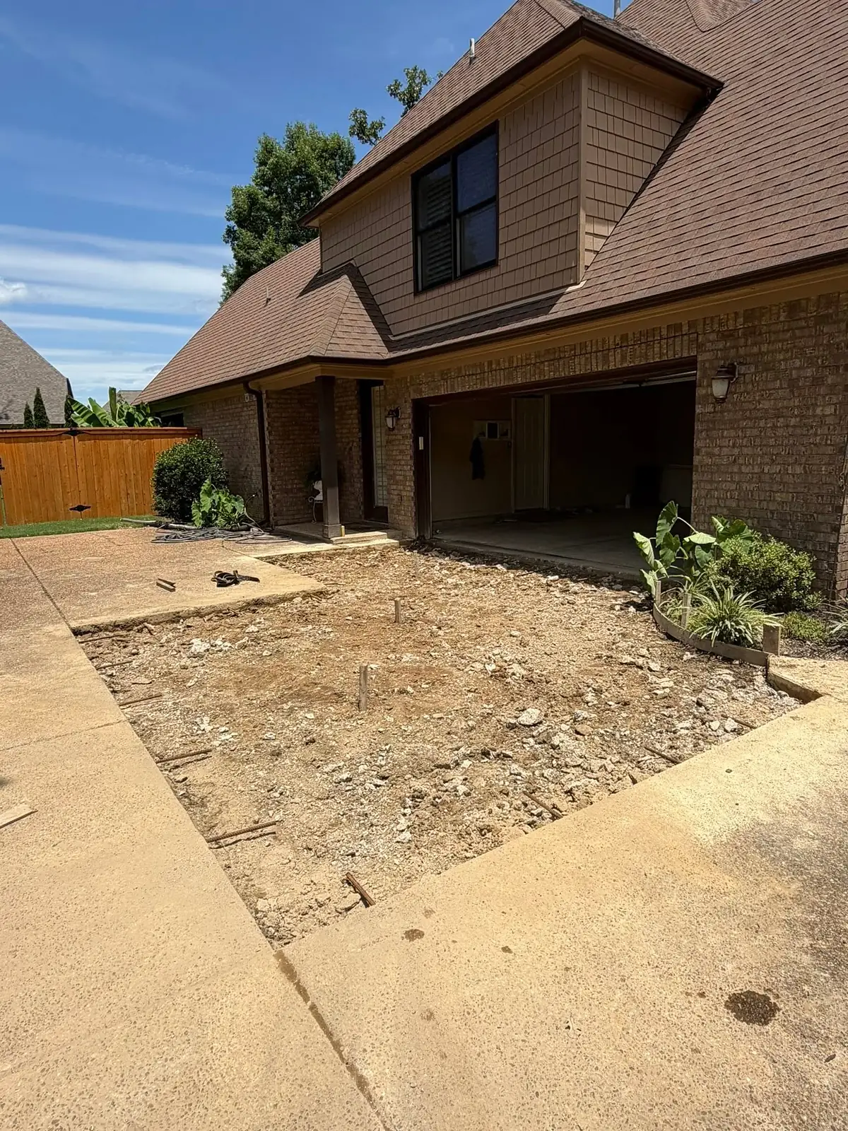 Section of old driveway torn out down to bare soil in front of a garage